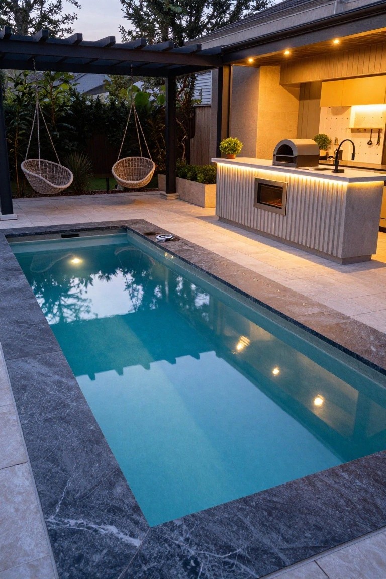 18 Luxury Pool Detail Ideas That Take Your Design Further Rectangular lap pool with dark marble coping and light travertine patio tiles around it, next to a modern outdoor kitchen bar with LED lighting under a pergola and hanging rattan chairs at dusk.