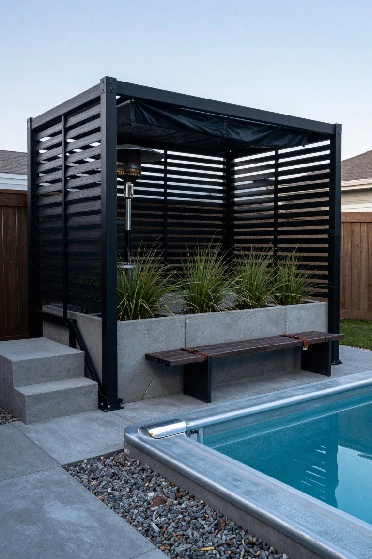 Black slatted metal pergola with fabric roof over a concrete bench, planter box with grasses, and patio heater, positioned next to an above-ground pool with pavers and steps.