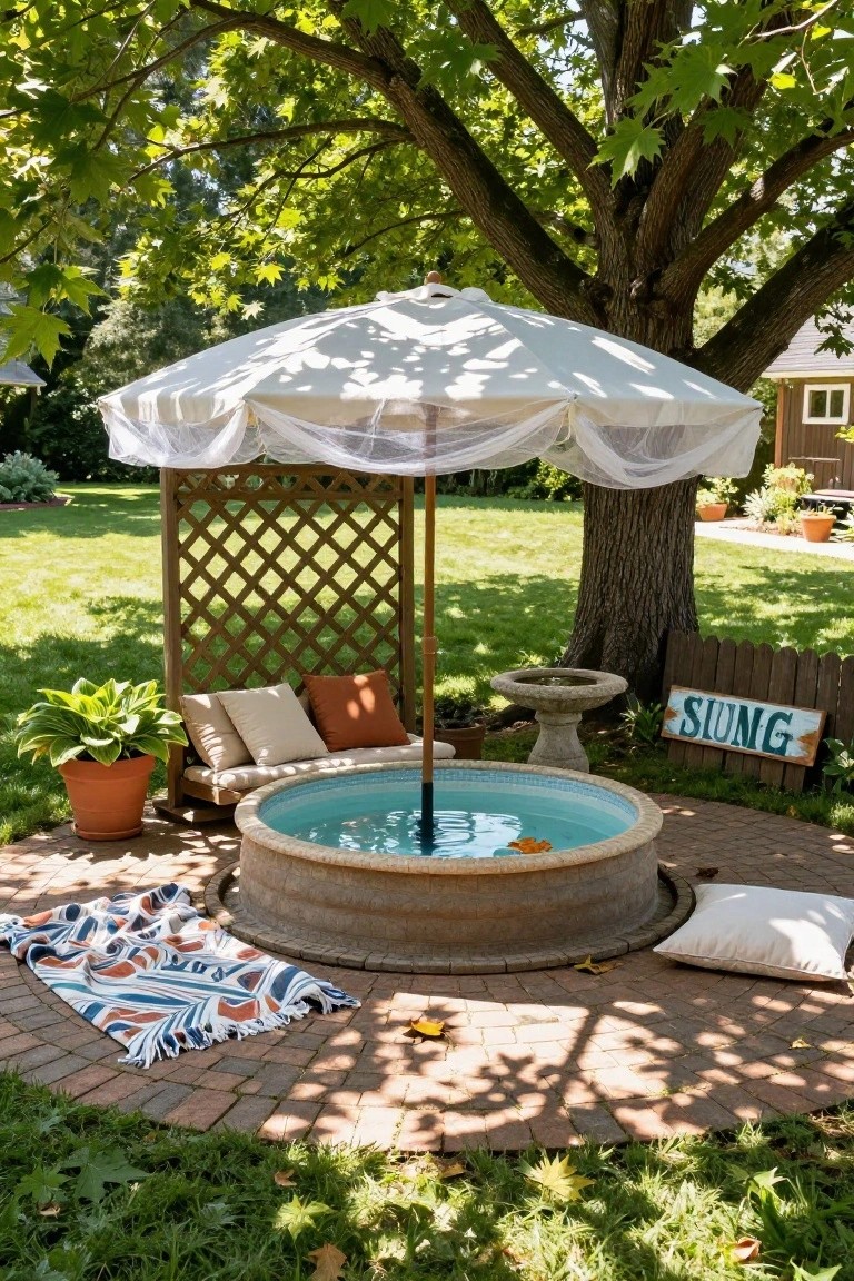 Round stock tank kiddie pool in a backyard patio shaded by a large white market umbrella with netting, surrounded by cushions, plants, a lattice screen, and a tree.