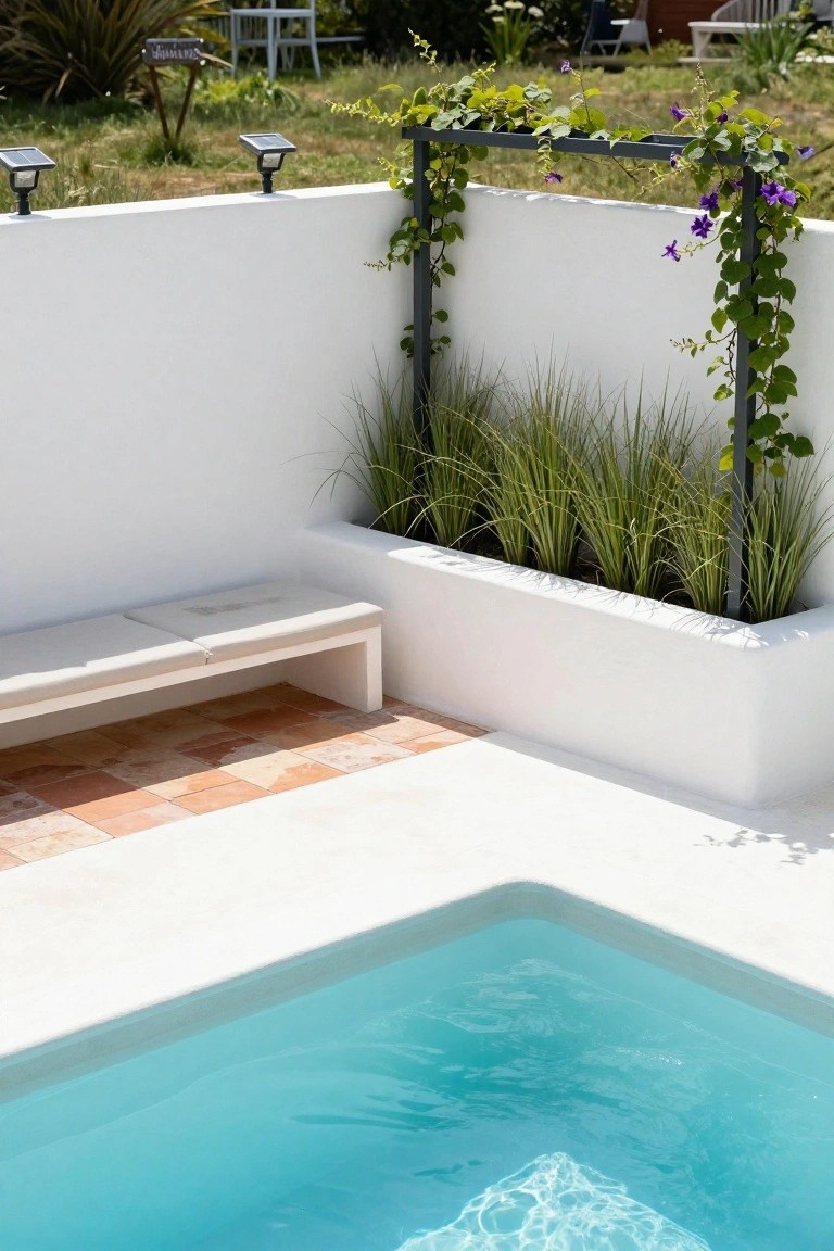 Corner inground pool with turquoise water next to a white built-in bench on terracotta tiles, raised white planter box filled with tall grasses, metal trellis with climbing purple vines against white stucco walls, and solar lights nearby.