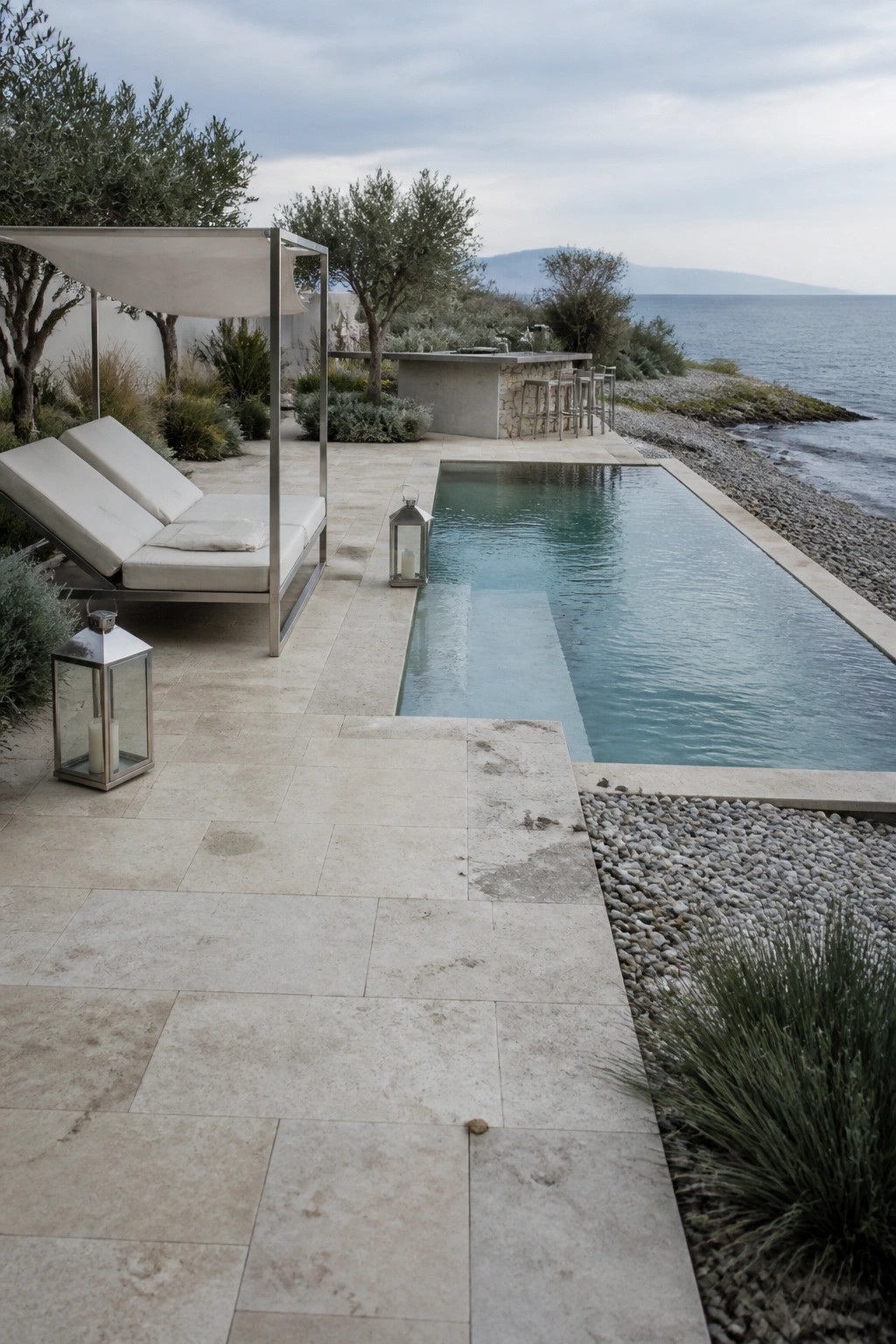18 Natural Stone Pool Patio Ideas That Blend Beautifully Into Landscaping Luxurious infinity pool with lounge chairs, lanterns, and ocean view on stone patio