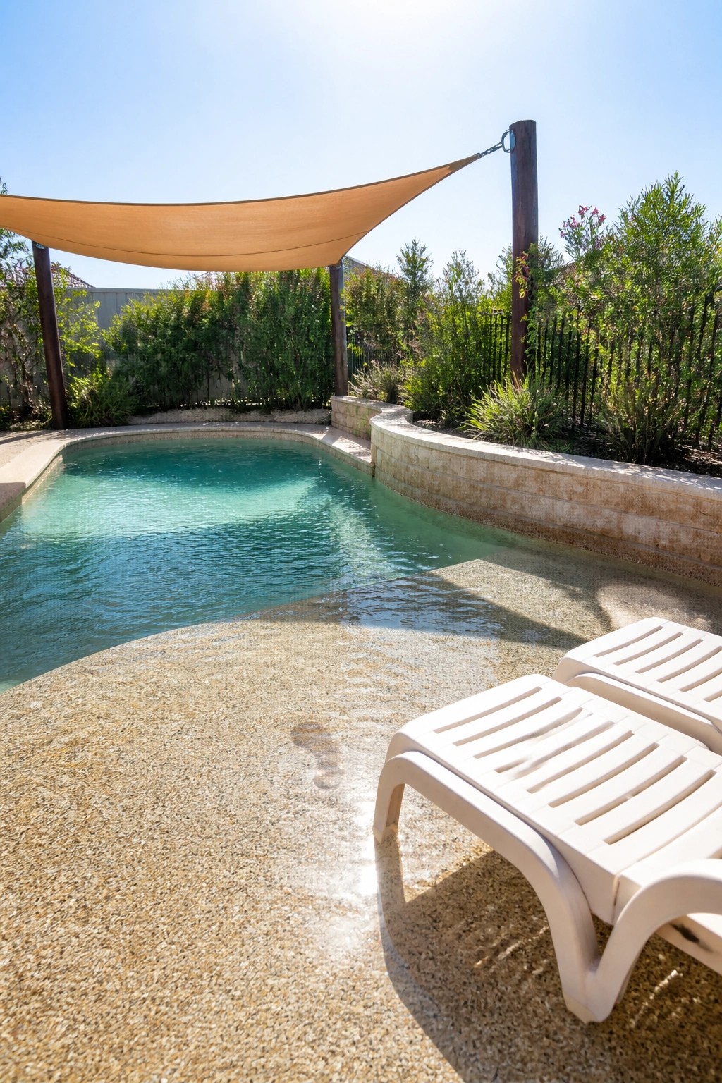 16 Affordable Small Pool Ideas on a Budget That Still Look Luxurious Swimming pool under tan shade sail with white lounge chairs on sunny deck