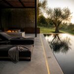 Narrow reflecting pool running along a terrace edge with concealed linear lighting and a tree-lined lawn beyond.