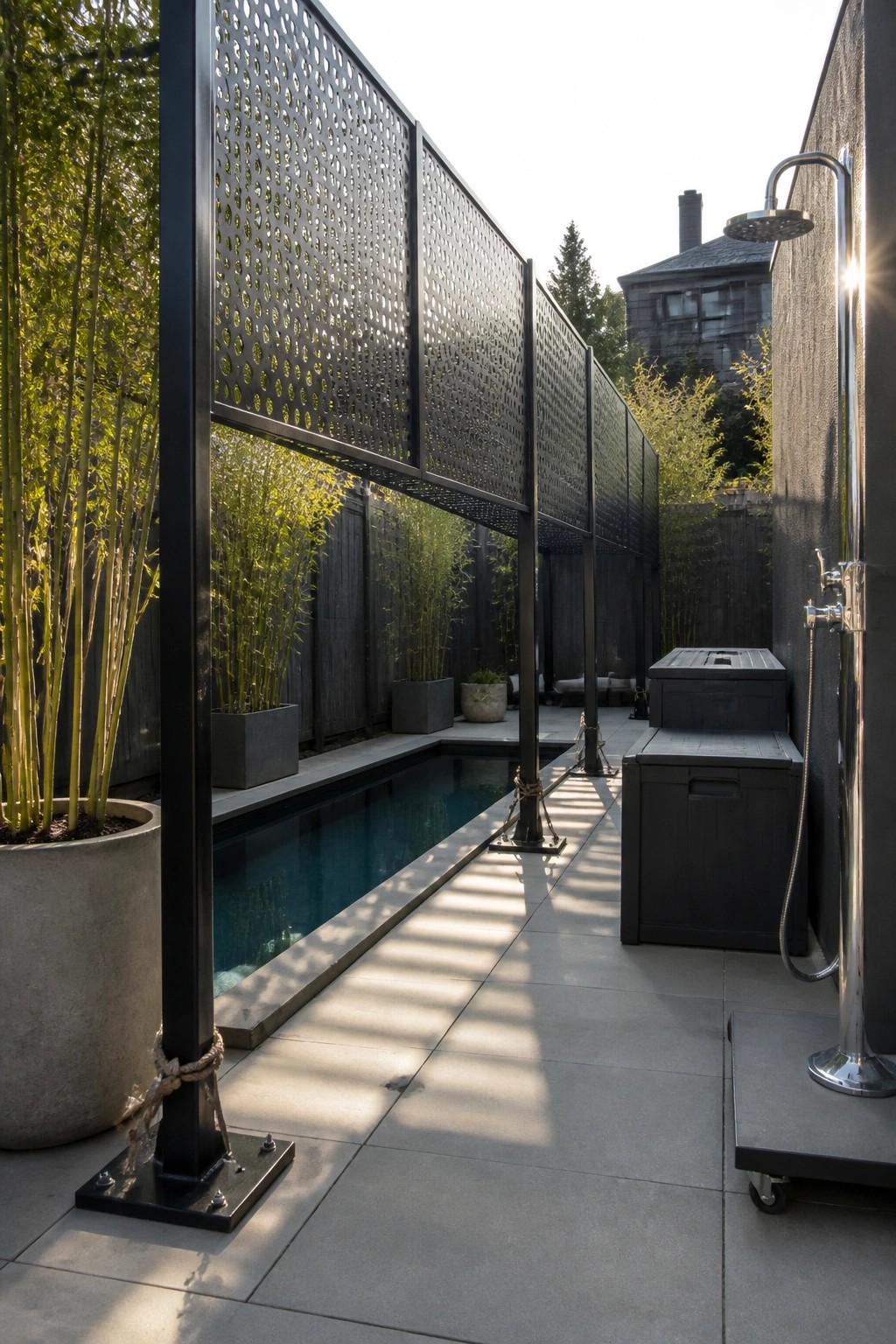 19 Versatile Temporary Pool Shade Ideas for Seasonal Pool Setups A narrow rectangular pool with a long overhead shade made of black perforated metal panels, concrete deck, potted bamboo plants, and an outdoor shower on the right.