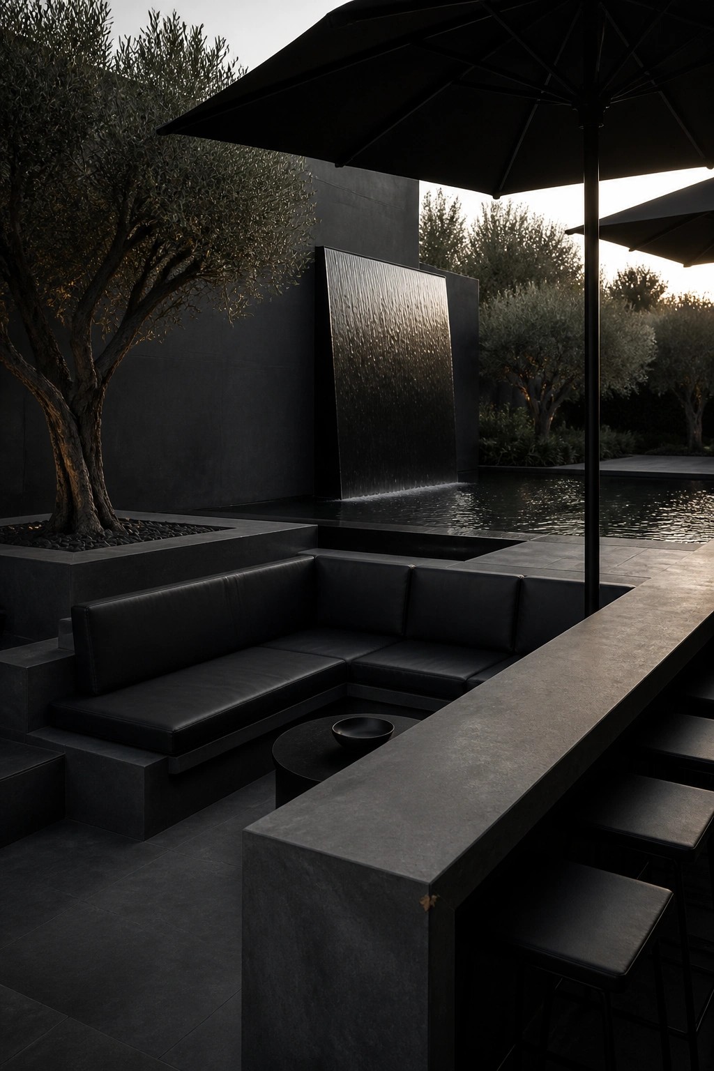 Sleek black outdoor patio with L-shaped sofa, bar, water wall, and trees