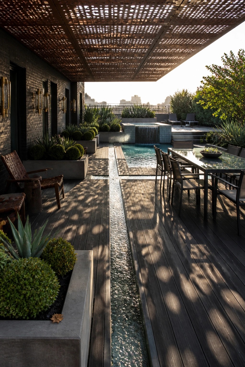 21 Smart Pool Deck Shade Ideas That Reduce Harsh Afternoon Sun An outdoor pool deck with dark wood flooring, a long narrow pool, a dining table with chairs, lounge seating, concrete planters, and a perforated metal overhead structure.