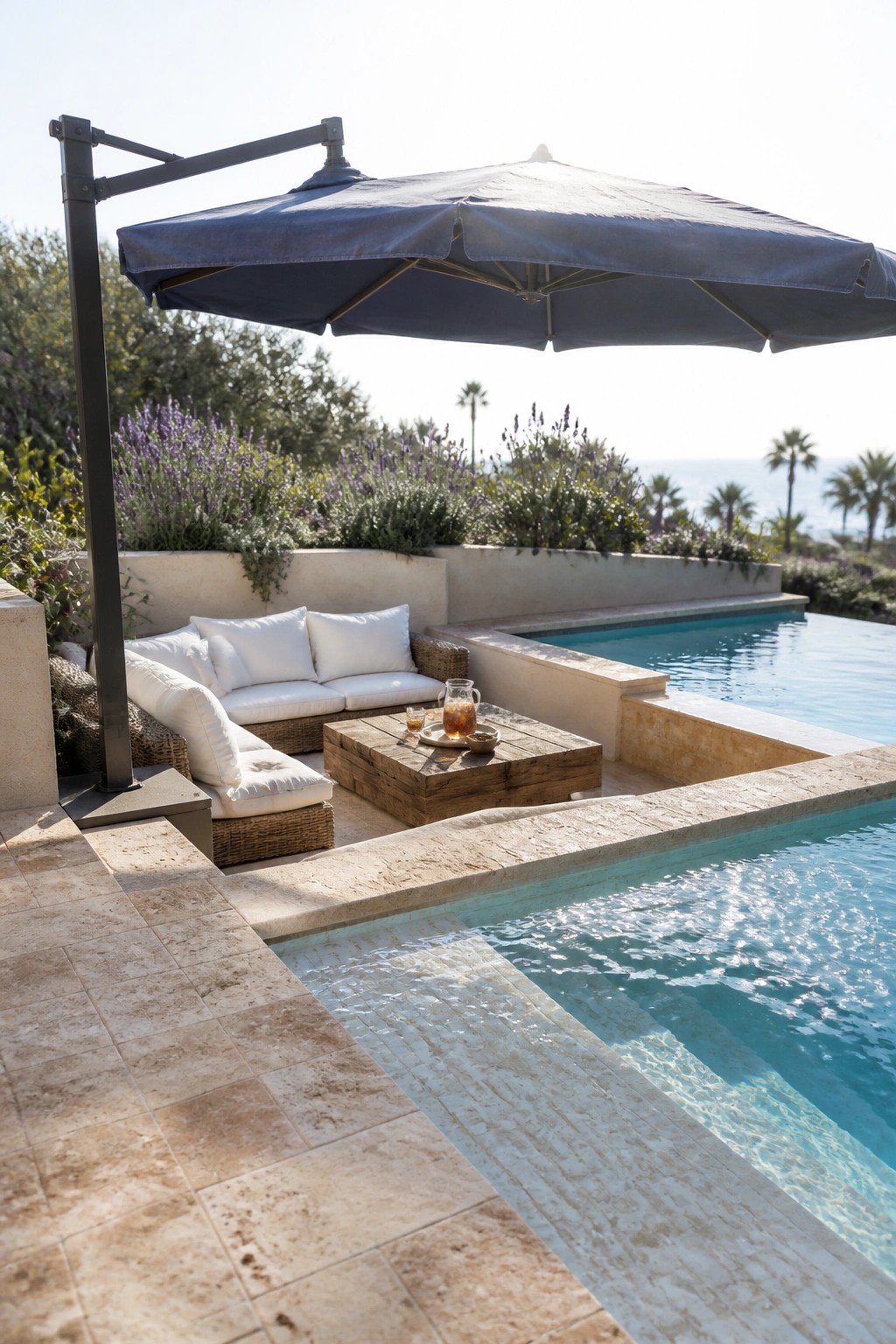 22 Stunning Pool Shade Ideas for Cooler and More Comfortable Pool Days A large blue cantilever umbrella shades a white cushioned outdoor sofa and wooden coffee table beside a swimming pool.