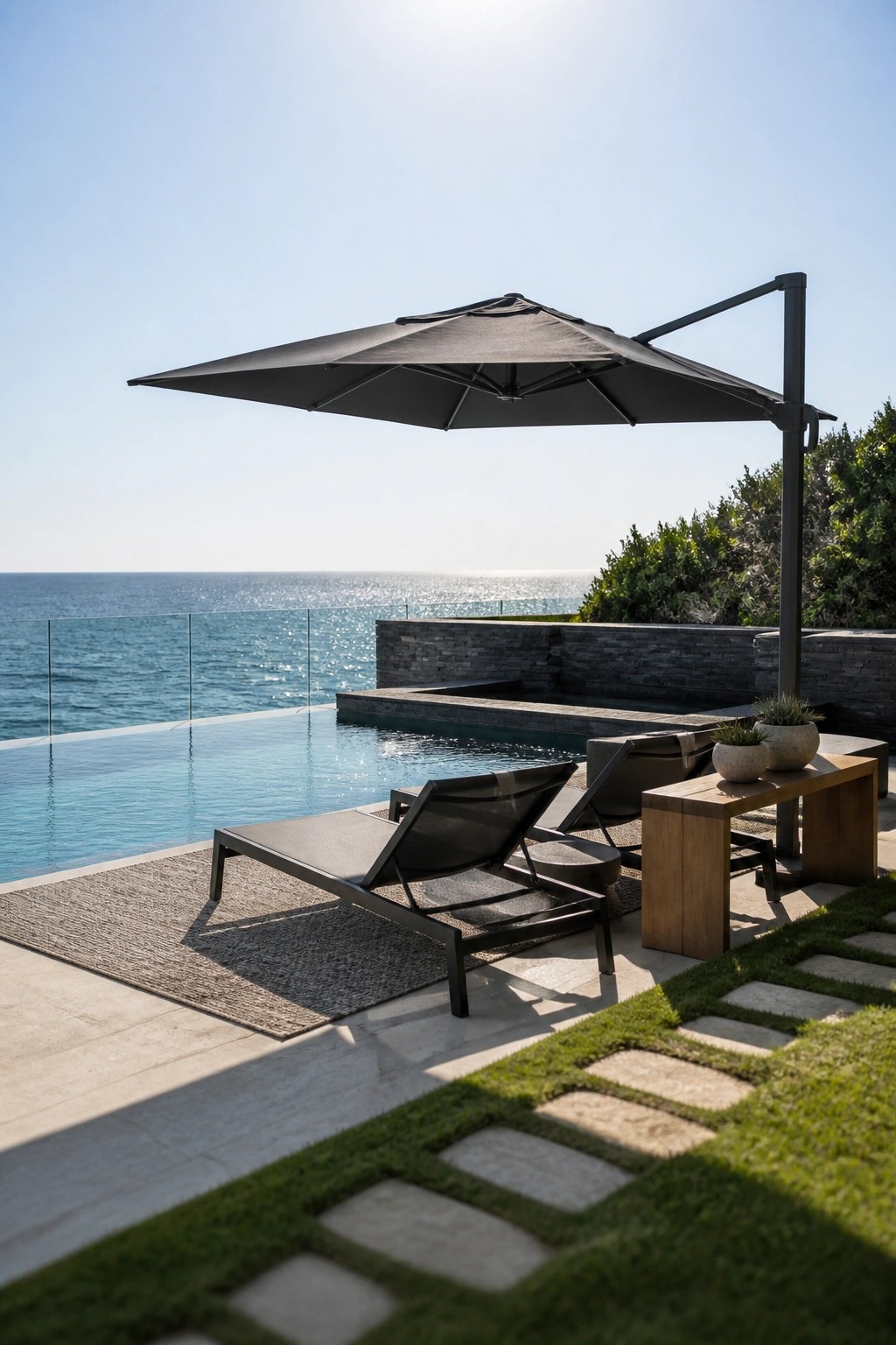 22 Contemporary Pool Shade Ideas in Minimalist Outdoor Settings A large black cantilever umbrella shades two dark lounge chairs on a stone deck next to an infinity pool with an ocean view.