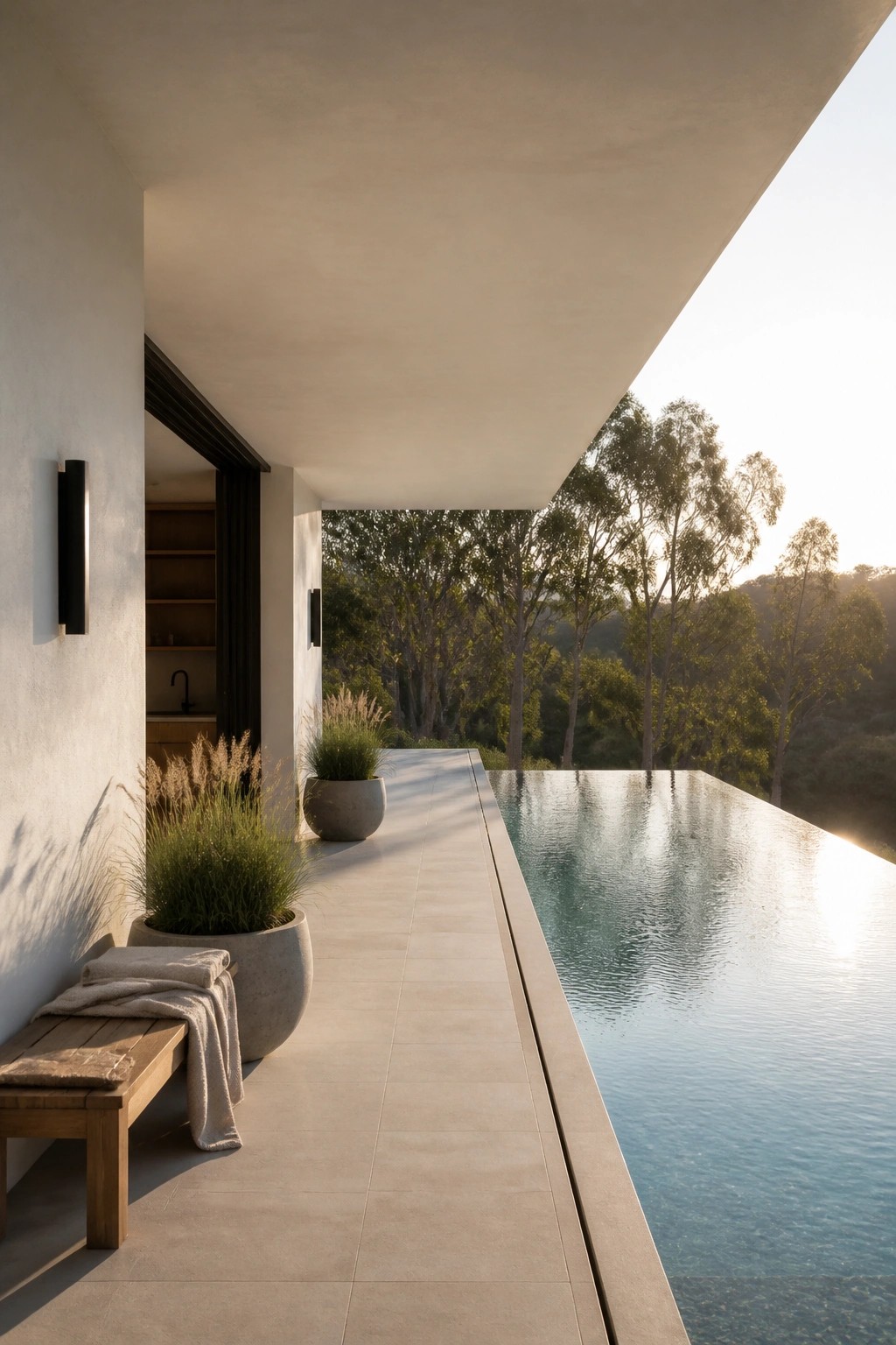 22 Contemporary Pool Shade Ideas in Minimalist Outdoor Settings Modern patio with infinity pool, potted grasses, wooden bench, overlooking sunlit forest.