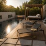 A narrow rectangular pool with a long wooden deck running along one side, furnished with dark lounge chairs and a small side table, plus a wooden pergola structure at the far end.
