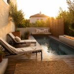 Wooden pool deck with two lounge chairs, a long built-in bench with pillows, large terracotta pots, and a small pool with a fire feature along the edge.