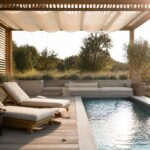 White lounge chairs on wooden deck beside sunlit pool under wooden pergola.