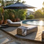 A large dark blue cantilever umbrella shades striped lounge chairs on a wooden deck beside a round above-ground pool.