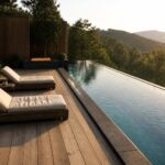 Modern wooden deck with lounge chairs beside infinity pool and fire pit at sunset