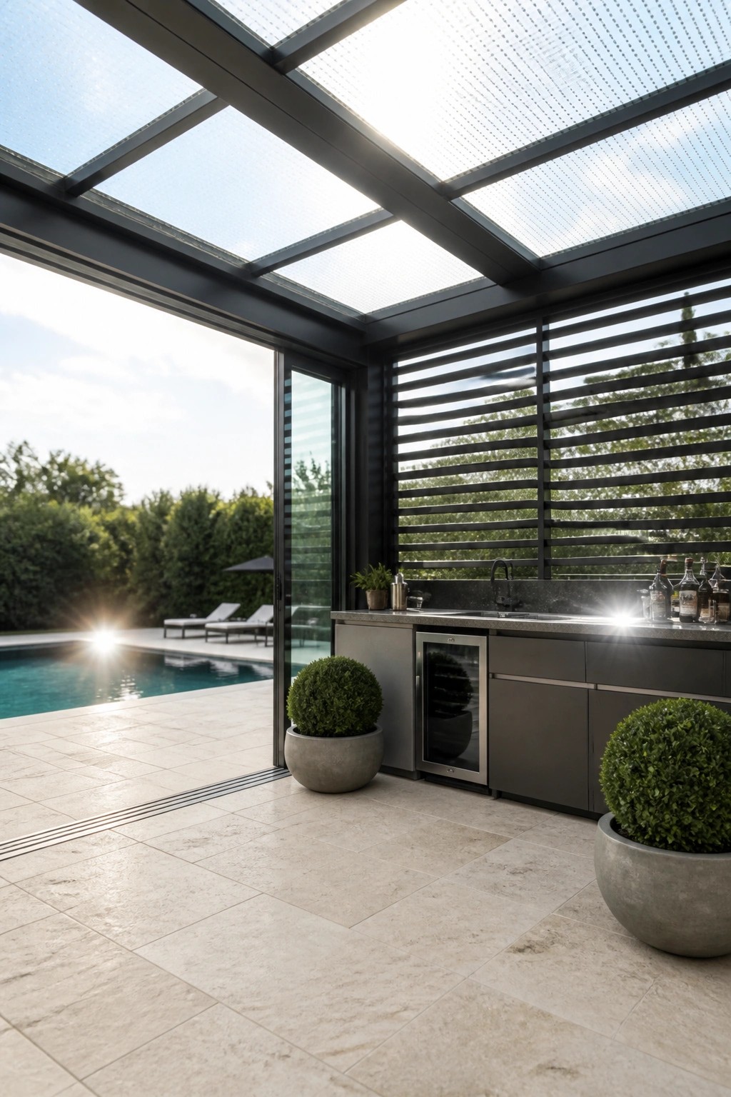 24 Inspiring Permanent Pool Shade Ideas Built for Long-Term Sun Protection Outdoor kitchen area with a glass roof and dark horizontal blinds positioned beside a swimming pool on a stone patio.