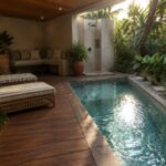 A long narrow plunge pool with pebble bottom sits beside a wooden deck with two striped lounge chairs, a built-in bench, potted plants, and an outdoor shower under a covered lanai.
