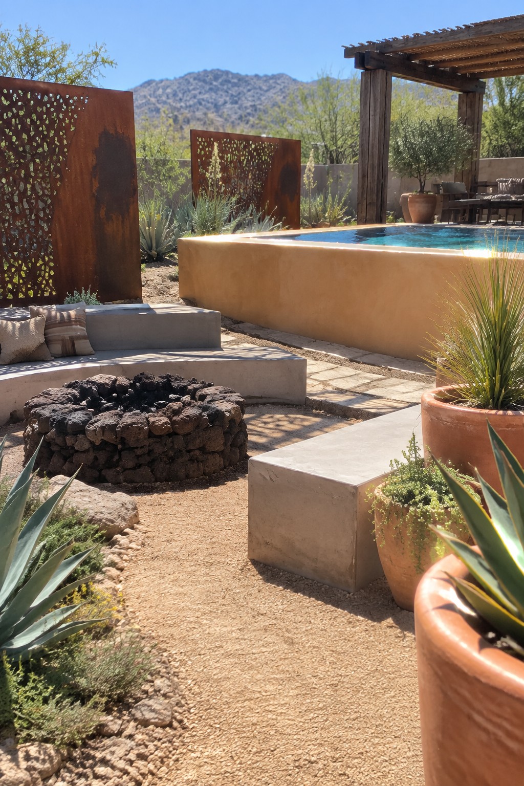 18 Inviting Above Ground Pool and Fire Pit Ideas for Backyard Entertaining Desert patio with pool, stone fire pit, concrete benches, rusted screens, and mountain backdrop.