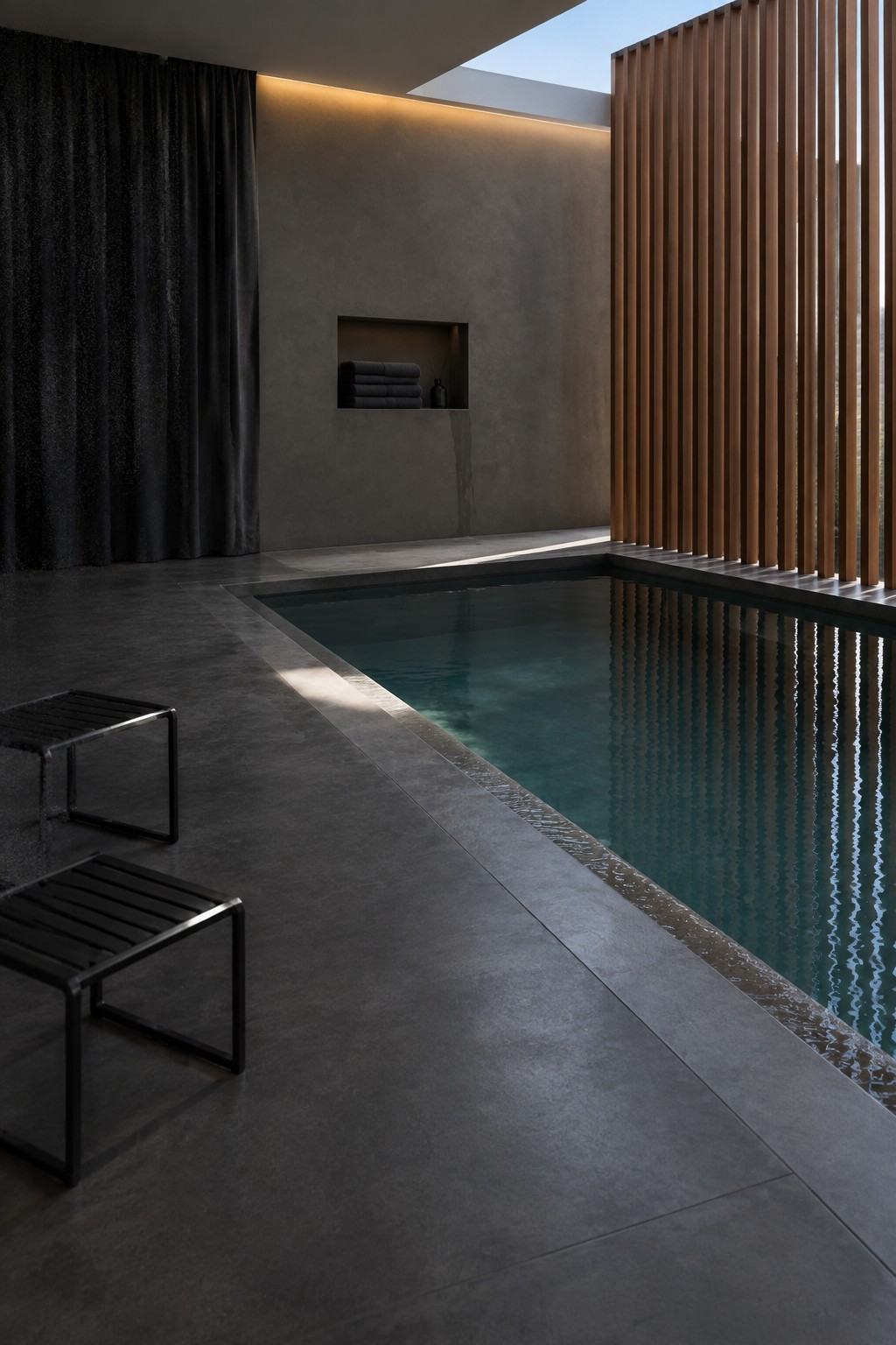 16 Serene Indoor Plunge Pool Ideas for Residential Spaces Modern indoor pool with dark concrete walls, black stools, and wooden slats