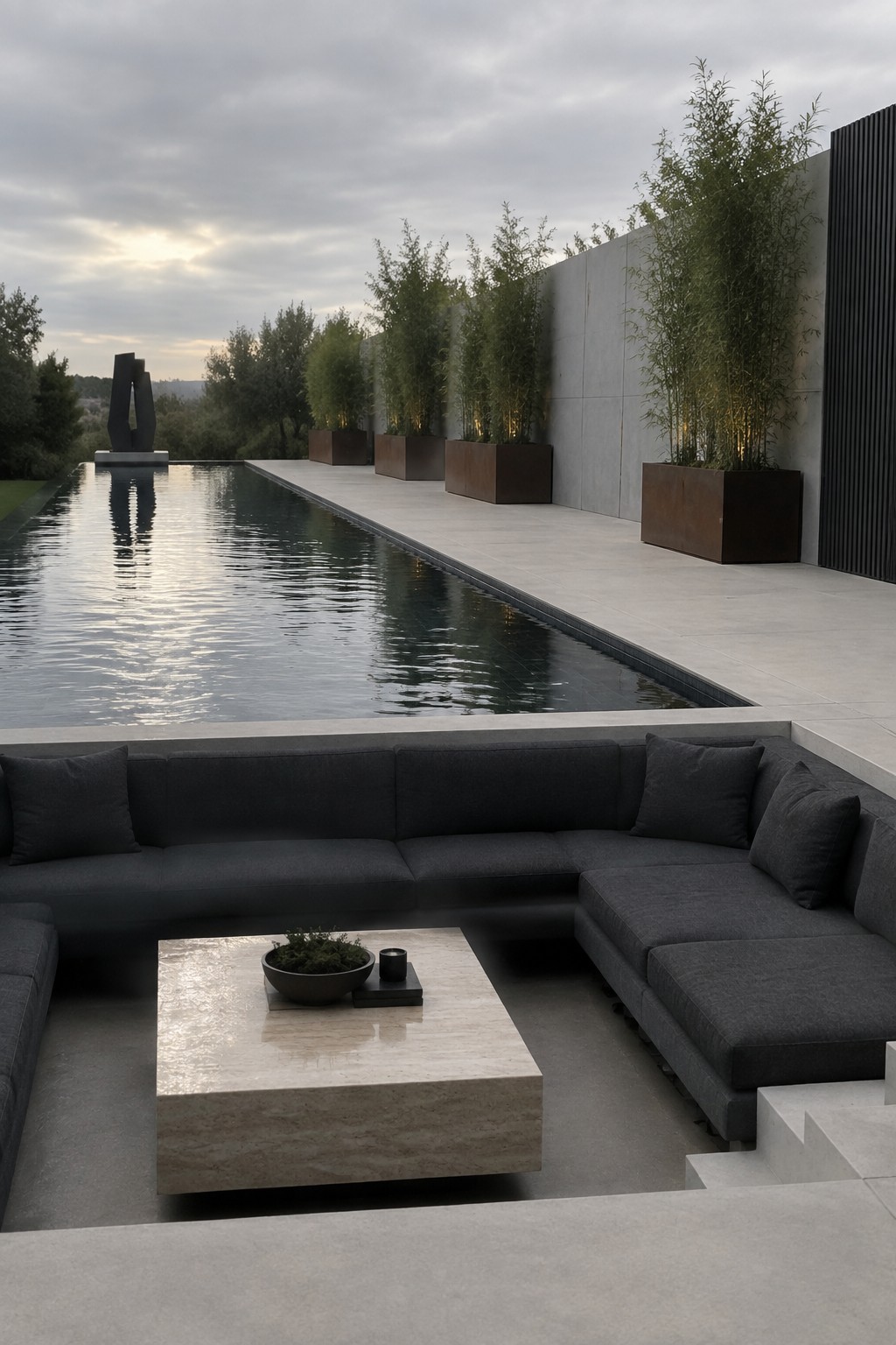 18 Stunning Backyard Infinity Pool Ideas With Modern Outdoor Layouts Modern patio with dark sectional sofa beside long pool and bamboo planters.