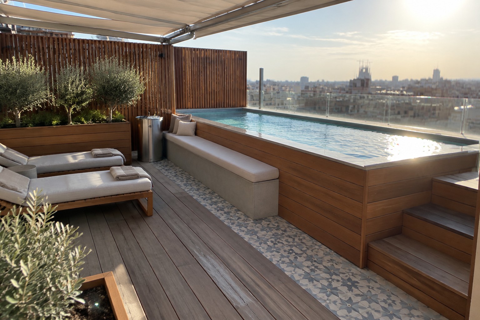 16 Striking Raised Plunge Pool Ideas for Level Changes and Compact Yards A raised rectangular plunge pool with light blue water is set into a wooden deck, with a concrete bench running along one side and two cushioned lounge chairs positioned nearby.