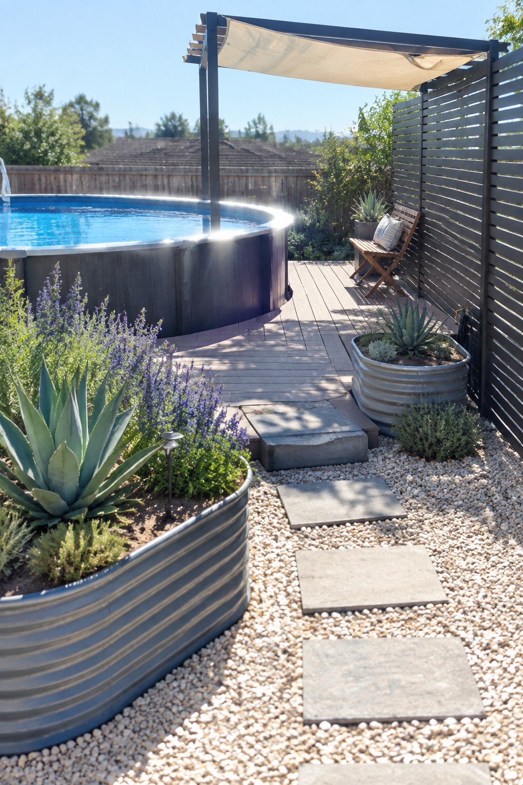 An above-ground pool on a wooden deck with a fabric shade structure overhead, gravel path with stepping stones, and large metal planters with succulents.