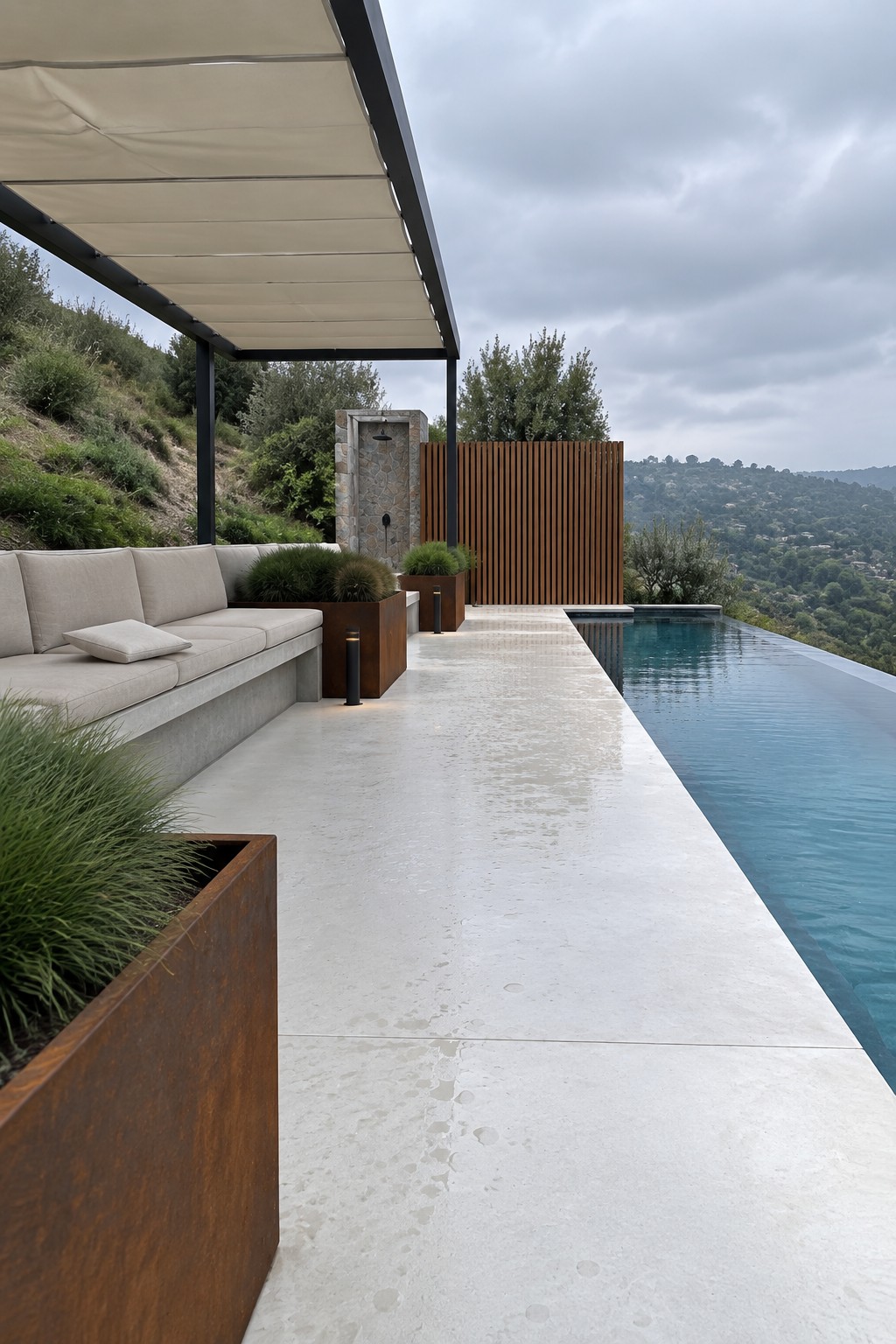 Modern patio with beige sofa, rusted planters, and infinity pool overlooking hills.