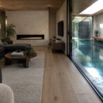 Modern living room with gray sofa, fireplace, wooden floors, and indoor pool