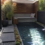 Modern plunge pool with cascading fountain, concrete bench, wooden wall, and stepping stones.