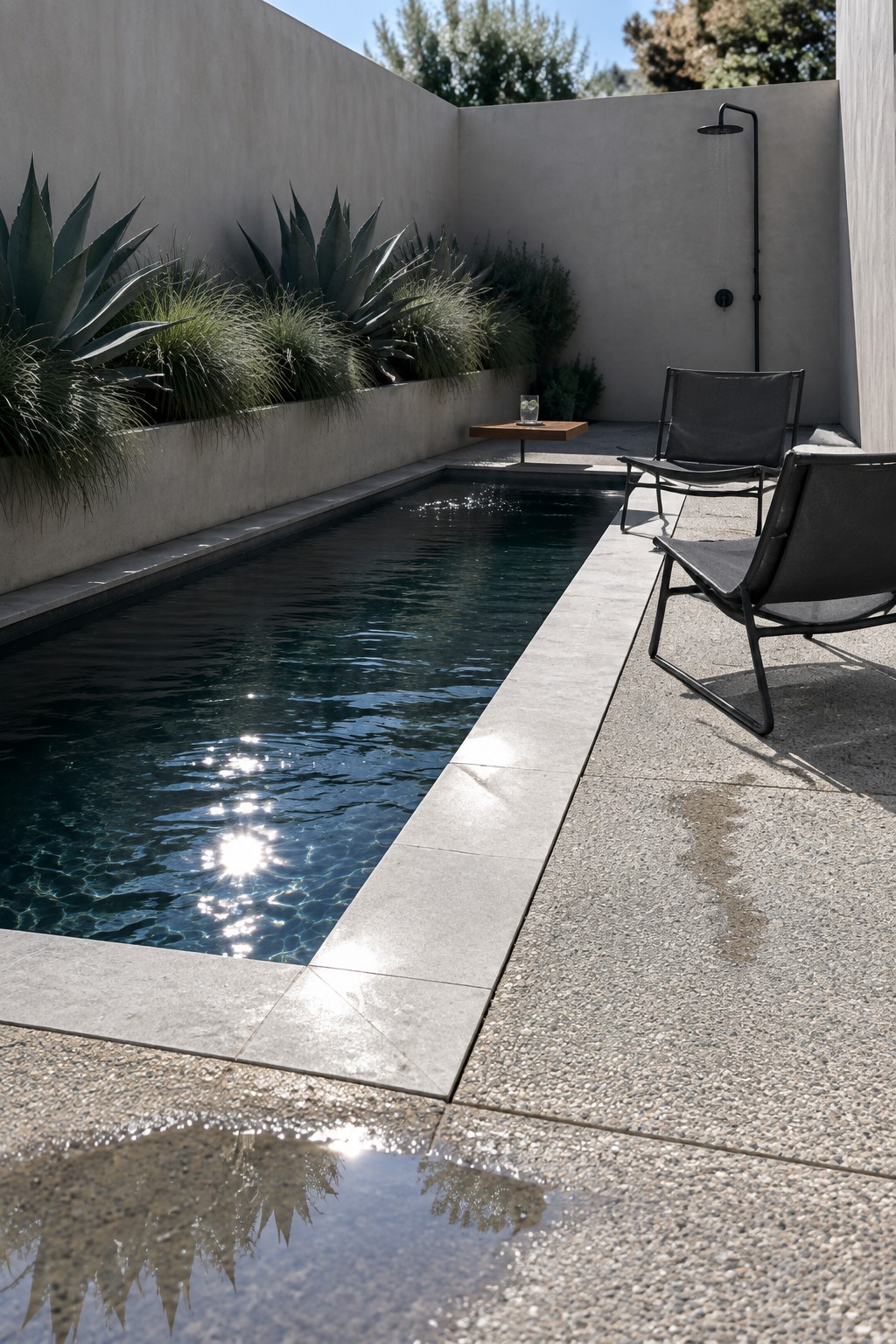 21 Fresh Plunge Pool Landscaping Ideas With Natural Stone Surrounds Modern lap pool with sunlit ripples, black lounge chairs, outdoor shower on concrete patio
