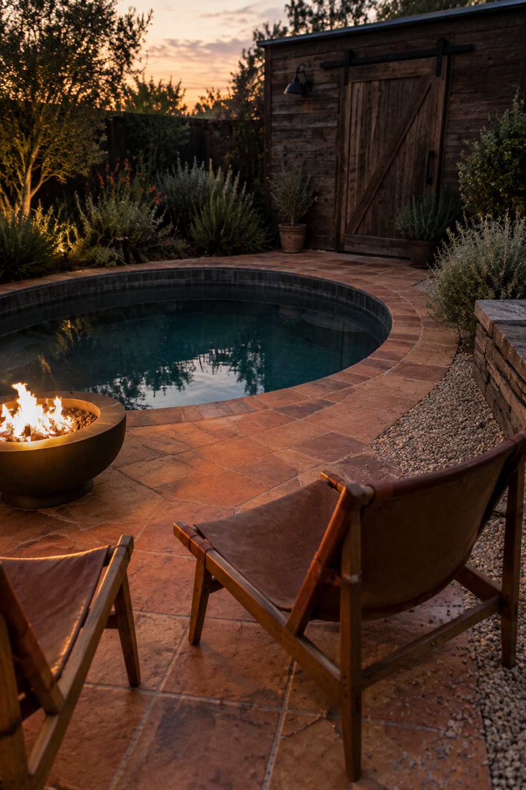 A round plunge pool with a fire pit and two sling chairs on a brick patio beside a wooden shed.